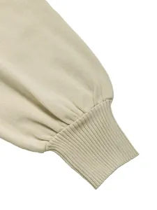Detail der Rippbündchen am beigen Strickkleid mit gefalteten Laternenärmeln