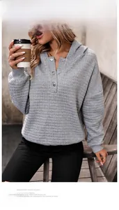 Detail of light grey waffle knit hoodie featuring half-button collar and ribbed cuffs