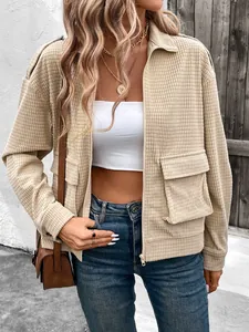 Detail of beige zip-up jacket featuring textured waffle fabric and large utility pockets