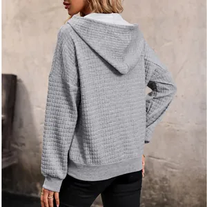 Back view of a gray waffle knit hoodie with relaxed drop shoulders and ribbed cuffs