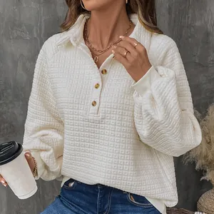 Detailed view of white waffle knit pullover with polo collar and amber buttons