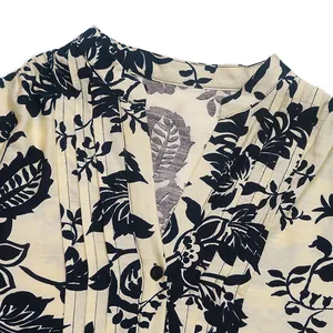 Detail of vintage floral blouse with V-neckline and intricate pleats on beige fabric
