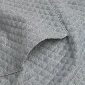 Close-up of grey waffle knit fabric texture showing quilted diamond pattern on casual top