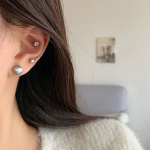 Modern brushed silver geometric stud earring set with zircon accents on a model's ear