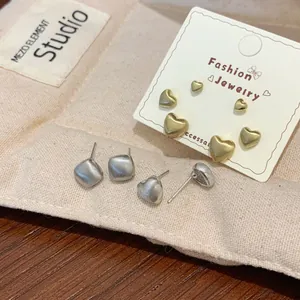 Minimalist brushed gold and silver heart stud earring set on jewelry card with gift pouch