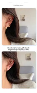 Detailed view of silver and gold zircon cross earrings worn on earlobe and cartilage