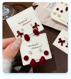 Macro detail of red flocked heart and bow stud earrings set with white pearl accents