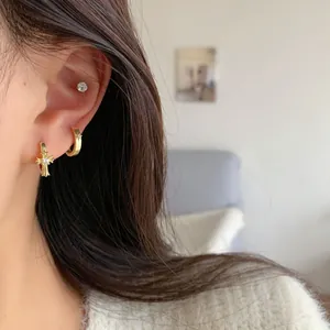 Golden zircon cross and butterfly hoop earrings set worn on ear in minimalist style