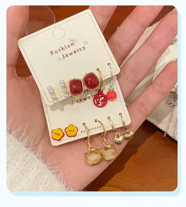 Detailed close-up of a diverse earring set featuring red, pearl, and gold designs
