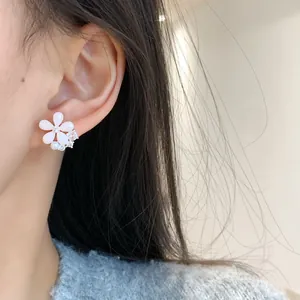 Orecchini a lobo a fiore rosa e bianco con zirconi e perle indossati da una modella