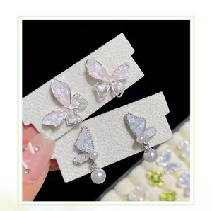 Close-up of crystal butterfly earrings with gradient resin wings and white pearl drops