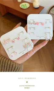 Detail der rosa Schmetterling- und Kirschblüten-Ohrringe im 7-Tage-Set auf einer Karte