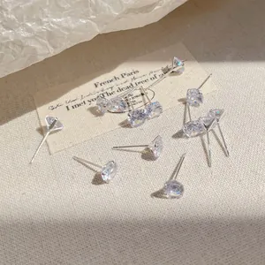 Elegant four-prong cubic zirconia silver stud earrings on a minimalist textured background