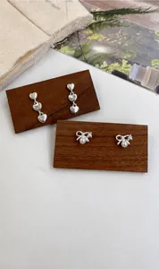 Detail of silver heart drop earrings and bow pearl studs on a rustic wooden display