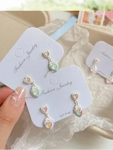 Dettaglio di orecchini a cuore con colori pastello e un fiocco rosa decorativo