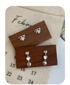 Detailed shot of bow earrings with pearls and silver heart drop earrings on wood