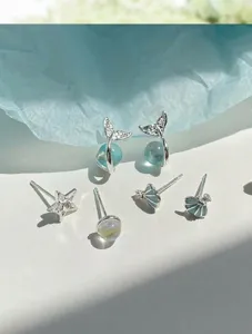 Dettaglio di orecchini a coda di pesce e conchiglia con perle blu oceano e argento