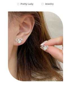 Close-up of bowknot pearl earrings showing the delicate silver plating and rhinestone details