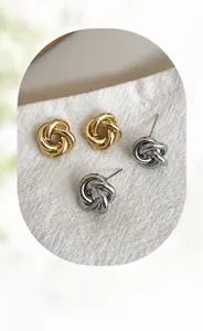 Détail de boucles d'oreilles nœuds entrelacés dorées et argentées sur lin doux