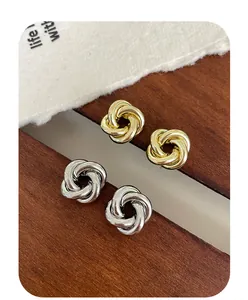 Vue détaillée de boucles d'oreilles nœud en or et argent sur une surface minimaliste