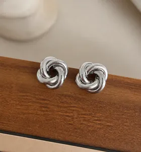 Gros plan sur des boucles d'oreilles nœud en argent poli sur fond de texture bois