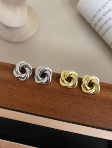 Gros plan de boucles d'oreilles nœuds métalliques minimalistes dorées et argentées