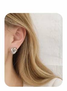 Vue détaillée de boucles d'oreilles nœud en argent poli portées par un mannequin