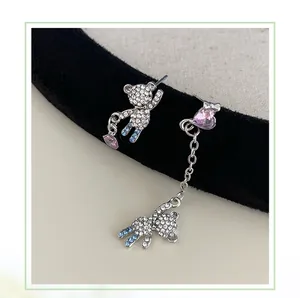 Detail of asymmetric silver bear earrings with blue rhinestones and pink heart charms