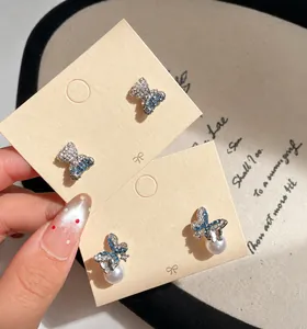Macro shot of blue zircon bear and butterfly earrings with a white imitation pearl drop