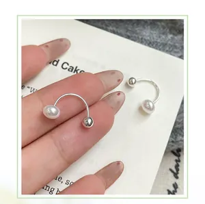Detail of silver U-shaped ear cuffs with elegant white pearls held in hand for size