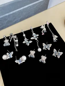 Detailed set of silver needle earrings featuring blue zircon bears and butterflies
