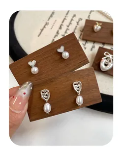 Dettaglio di orecchini a cuore con perle esposti su una base in legno vintage