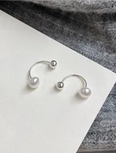 Macro shot of minimalist silver U-shaped ear cuffs with elegant white pearls and beads