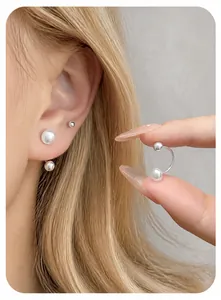 Close-up of minimalist U-shaped ear cuffs with white pearls and silver metal balls