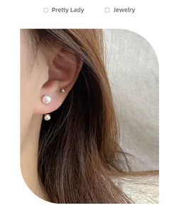 Detailed view of white pearl and silver ball ear cuffs worn on earlobe and cartilage
