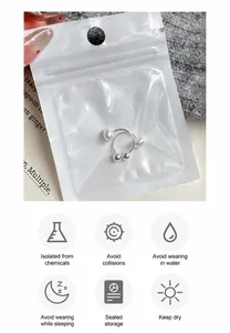 Detail view of pearl U-shaped ear clips in packaging with jewelry maintenance instructions