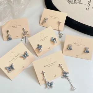 Elegant silver bear and butterfly earrings set with blue crystals and pearls on card