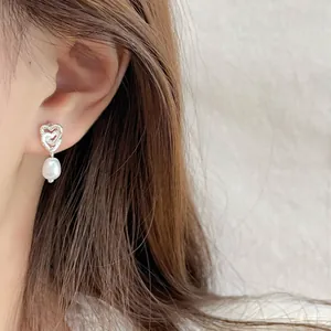 Orecchini in argento con doppi cuori intrecciati e pendenti di perle bianche sulla modella