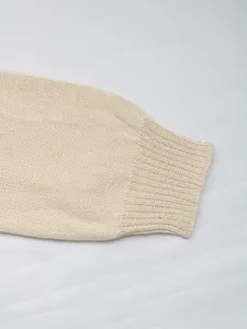 Close-up of cream knit sweater showing the fine texture and elastic ribbed cuffs
