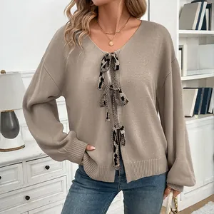 Detailed close-up of oatmeal knit cardigan featuring V-neck and leopard print tie bows