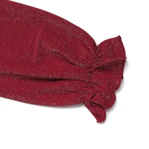 Macro detail of wine red sequin jumpsuit showing ruffled cuffs and sparkling metallic fabric