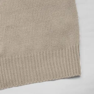 Close-up of beige knit cardigan showing fine stitching and ribbed hem detail