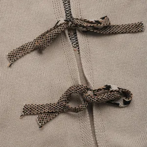 Macro shot of beige knit cardigan fabric with geometric jacquard tie-up detail