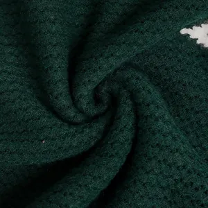 Close-up of deep green waffle knit fabric texture on a vintage pullover sweater
