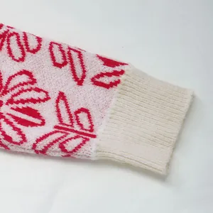 Dettaglio di maglione in maglia jacquard floreale rosa e rossa con polsini bianchi a coste