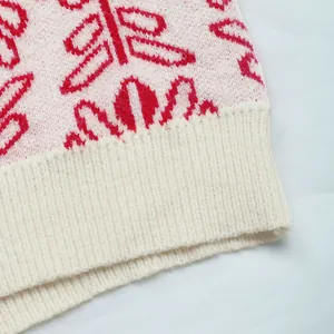 Vista dettagliata del motivo jacquard floreale rosso e dell'orlo a coste sul maglione