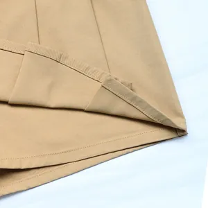 Dettaglio macro di una gonna a pieghe kaki con tessuto in twill e doppia cucitura
