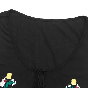 Détail d'un haut noir à col rond avec imprimé floral éclatant et cordons de serrage