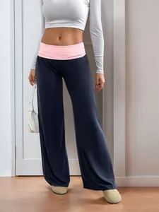 Detail of wide-leg trousers featuring a pink fold-over waistband and navy blue fabric