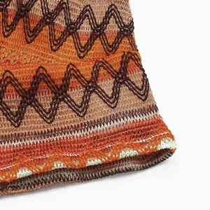 Dettaglio macro della trama in maglia a zigzag con strisce arancioni e marroni sul top